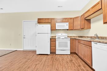 A kitchen with white appliances and wooden cabinets.